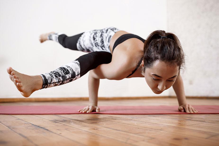 mlada žena se namešta za joga pozu Astavakrasana