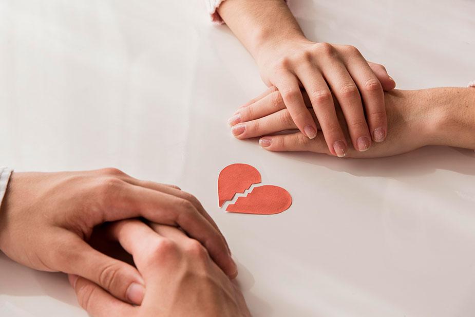 muške i ženske šake svaka posebno prekrštena između pocepana slika srca koja asocira na razvod braka