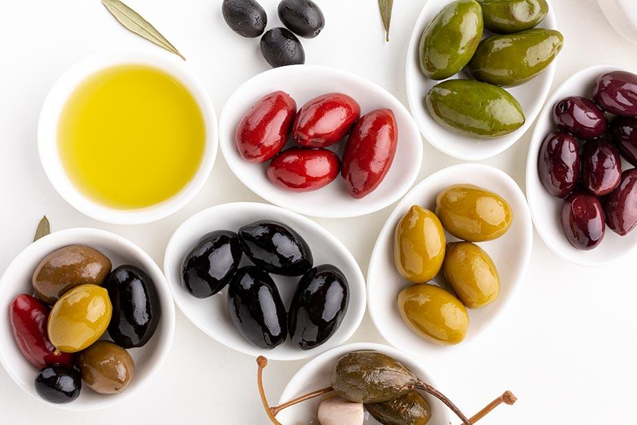 Različite vrste maslina: zelene, crvene, tamne i posuda sa maslinovim uljem