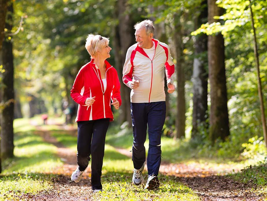 stariji par upražnjava trčanje kroz šumu