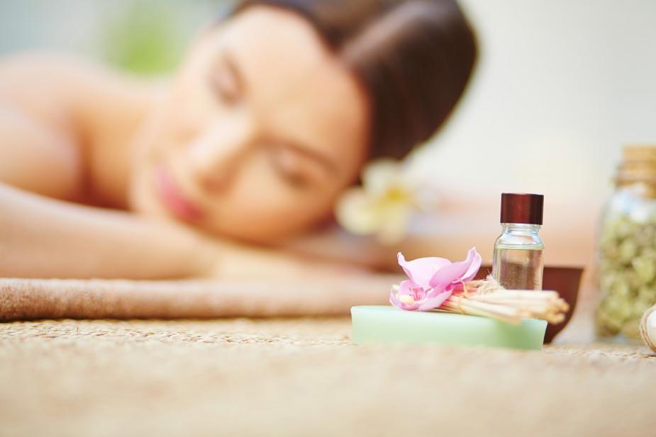 žena na tretmanu - leži na stomaku isped nje peškir i bočica sa uljem