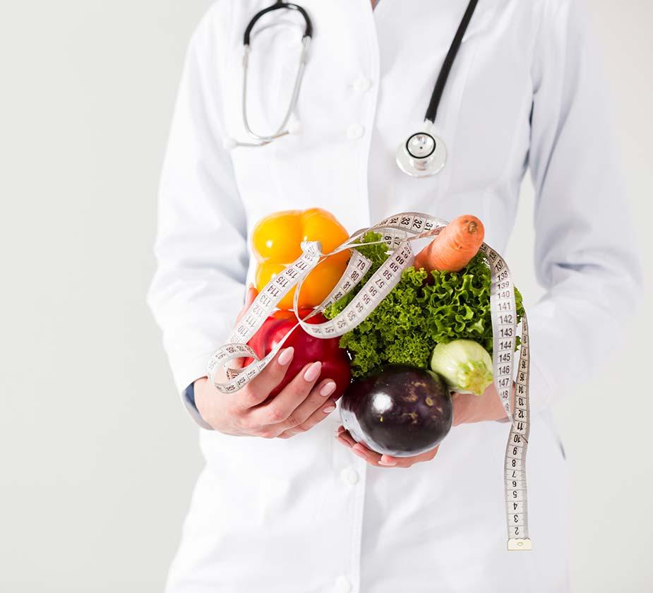 lekar sa stetoskopom oko vrata drži povrće i metar za merenje struka