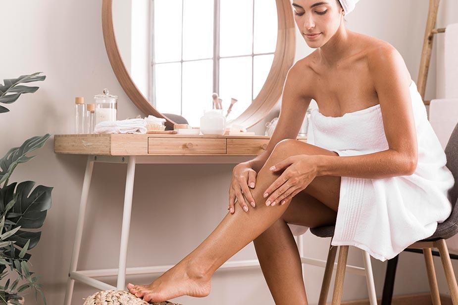 ženska osoba sedi i maže noge kremom