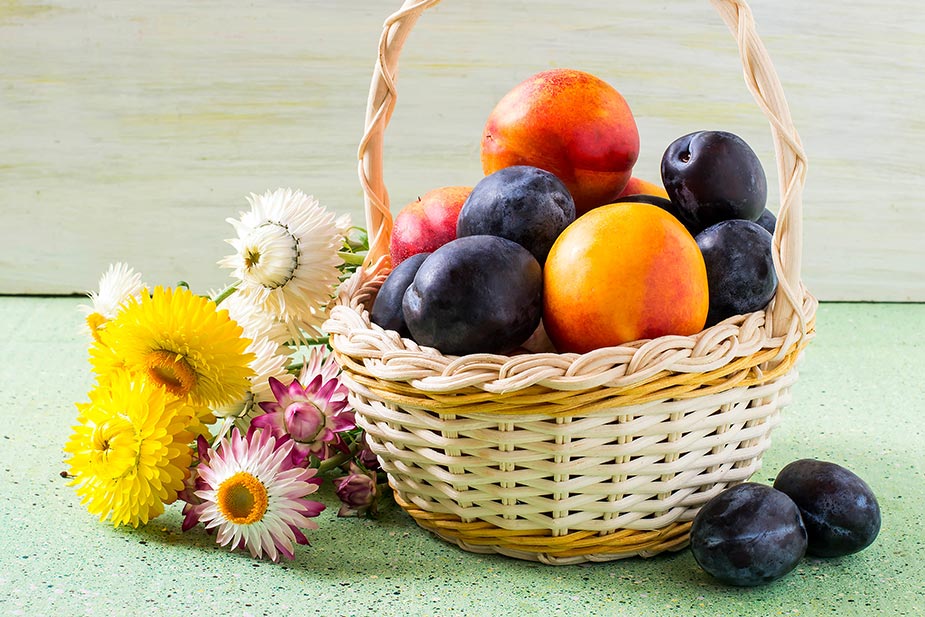 Korpa sa slasnim voćem: breskve i šljive, pored buket cveća - Šećer u voću