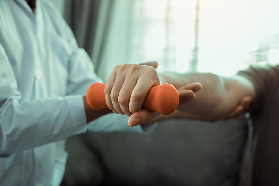 Terapeut pomaže pacijentu da vežba za tegićima ruku