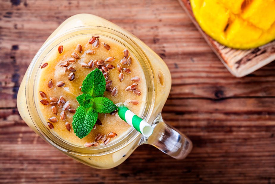 Čaša šejka gledana odozgo ukrašena listom nane i semenom lana - Laneno seme