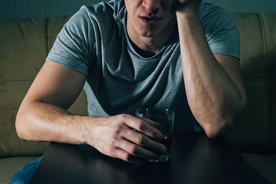 Usamljeni muškarac pije za stolom - alkoholizam