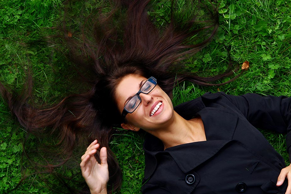 Mlađa žena leži na travi i mašta