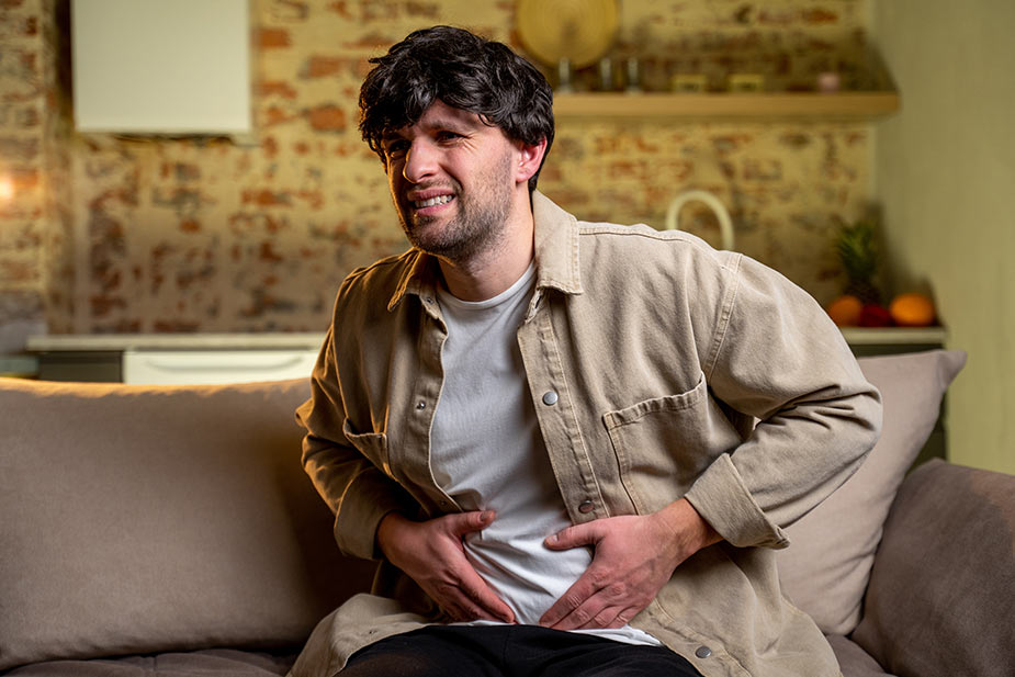 Mlađi čovek se drži za stomak jer ga muči želudac